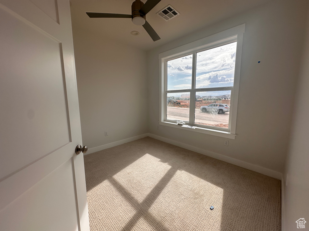 Spare room featuring light carpet, ceiling fan, and plenty of natural light