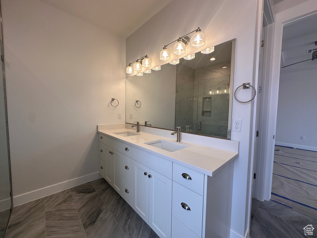 Bathroom featuring double vanity and a marble finish shower