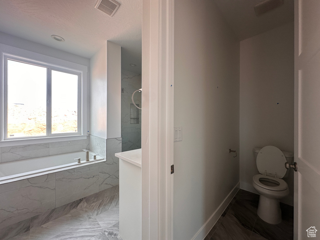 Bathroom featuring marble finish flooring and tiled tub