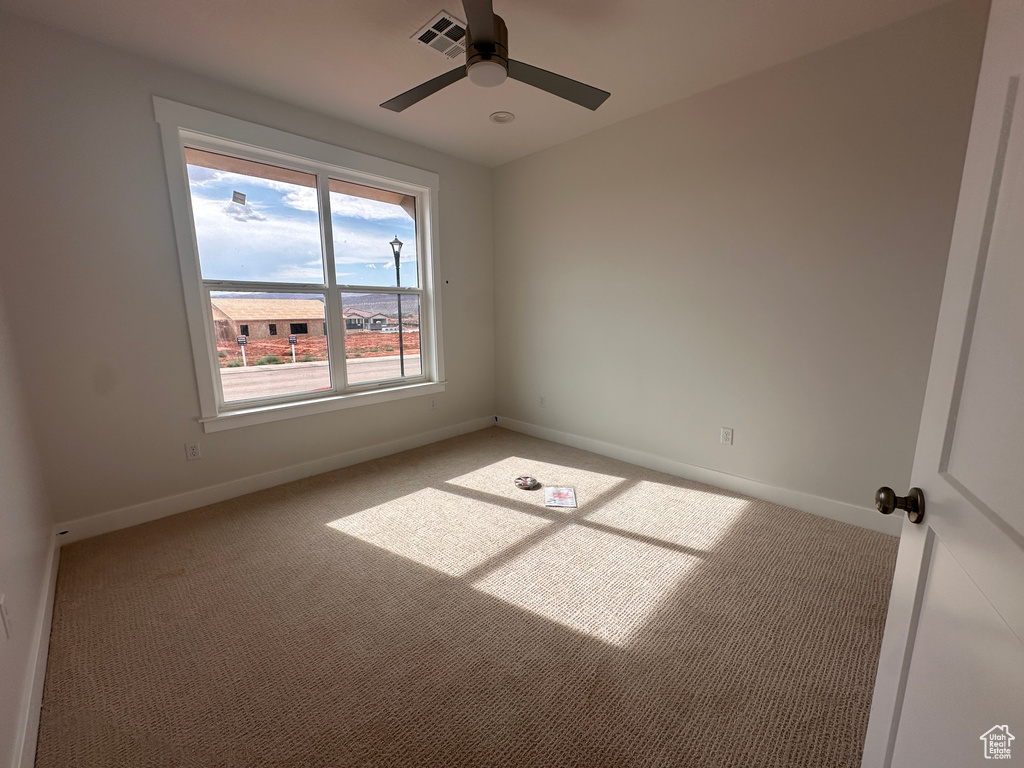 Carpeted empty room featuring a ceiling fan and baseboards
