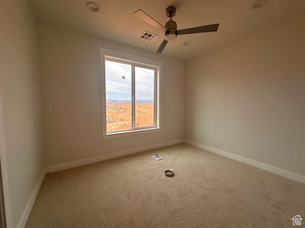 Unfurnished room featuring light carpet and a ceiling fan