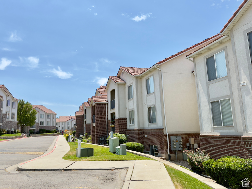 View of asphalt street with a residential view, sidewalks, and curbs