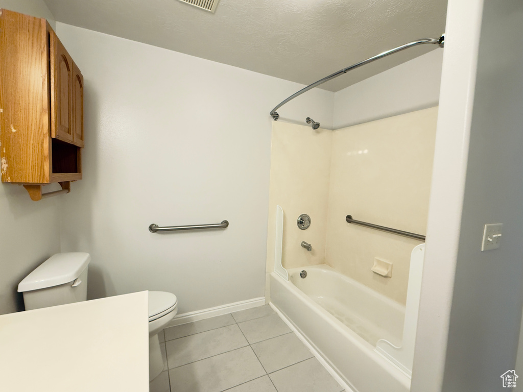 Bathroom featuring tile patterned flooring, shower / washtub combination, and a textured ceiling
