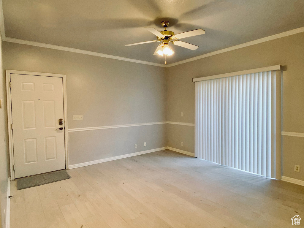 Unfurnished room featuring ceiling fan, light wood-style floors, and crown molding