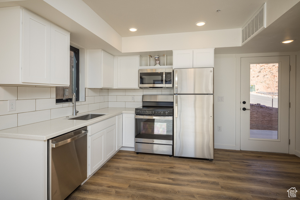 Kitchen with stainless steel appliances, a sink, open shelves, white cabinetry, and recessed lighting