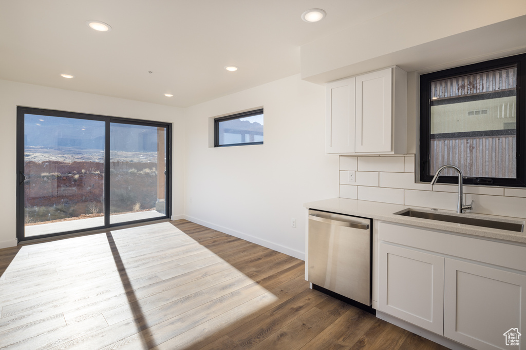 Kitchen with dishwasher, a sink, dark wood-style flooring, baseboards, and white cabinetry