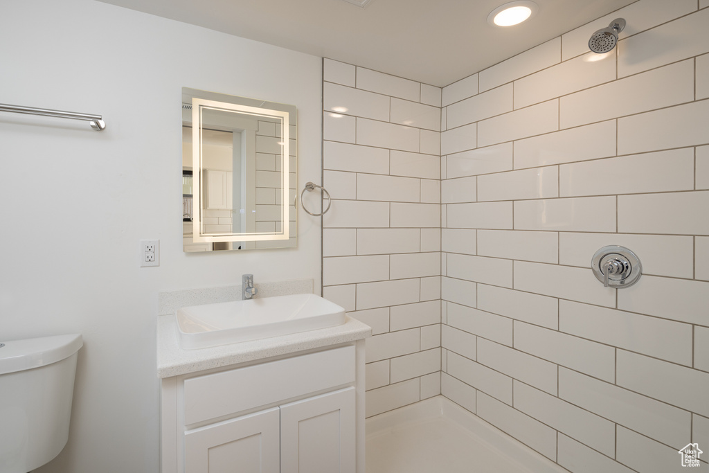 Bathroom featuring tiled shower, vanity, and toilet