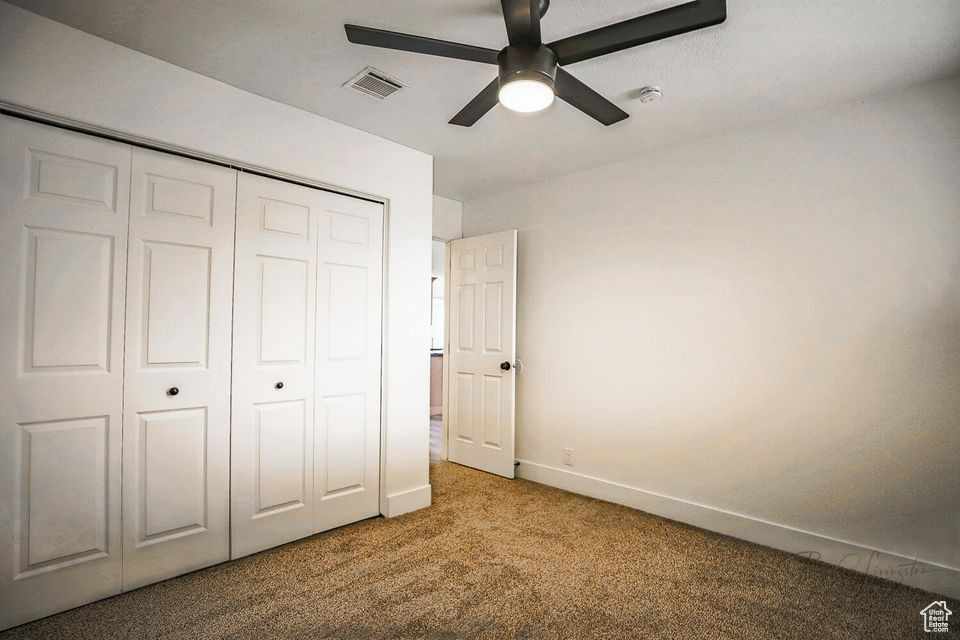 Unfurnished bedroom with carpet flooring, ceiling fan, and a closet
