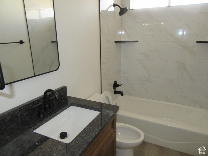 Full bathroom featuring tiled shower / bath combo, vanity, and toilet