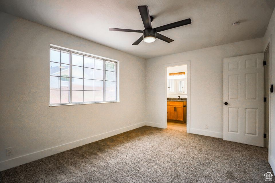 Unfurnished bedroom featuring ensuite bathroom, sink, light carpet, and ceiling fan