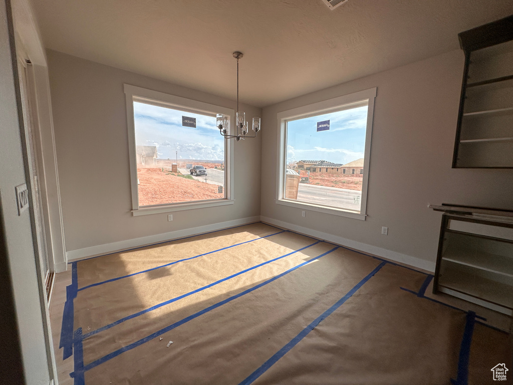 Unfurnished dining area featuring baseboards and a chandelier