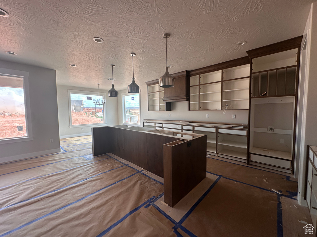 Kitchen featuring open shelves, a kitchen island, dark brown cabinetry, a textured ceiling, and recessed lighting