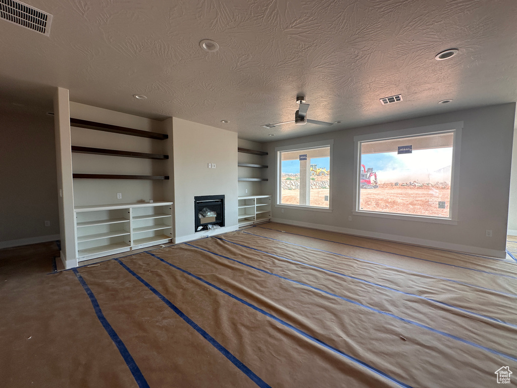 Unfurnished living room with a textured ceiling, built in shelves, a fireplace, and recessed lighting
