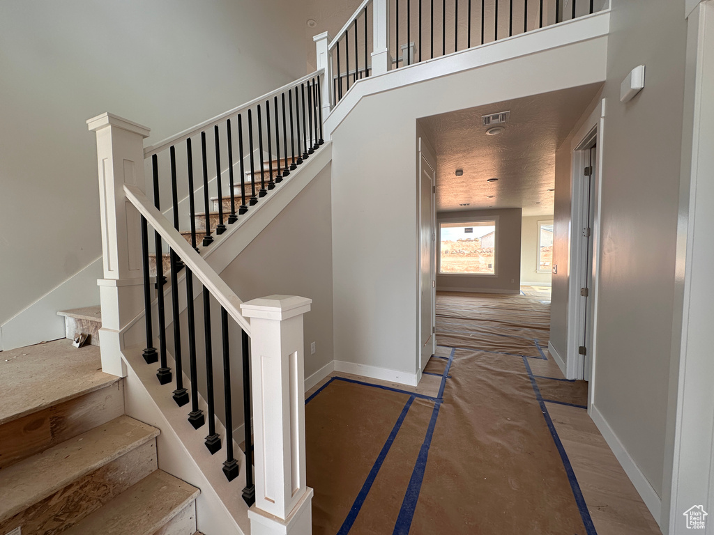 Staircase featuring baseboards and a high ceiling
