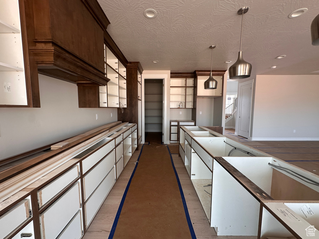 Kitchen featuring decorative light fixtures, recessed lighting, white cabinets, a textured ceiling, and light wood finished floors