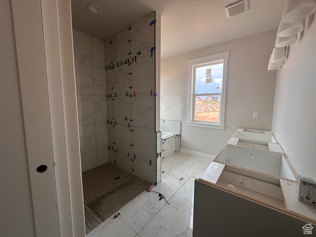 Bathroom featuring a stall shower, vanity, and marble look tile flooring