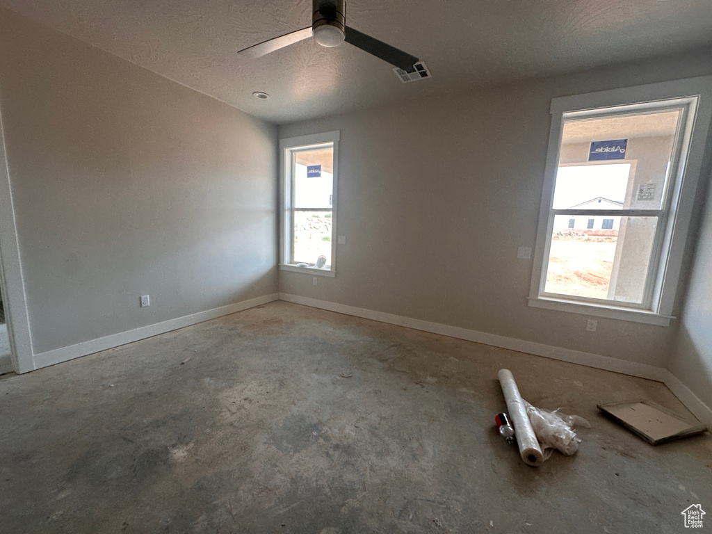 Spare room with unfinished concrete flooring, a ceiling fan, and a textured ceiling