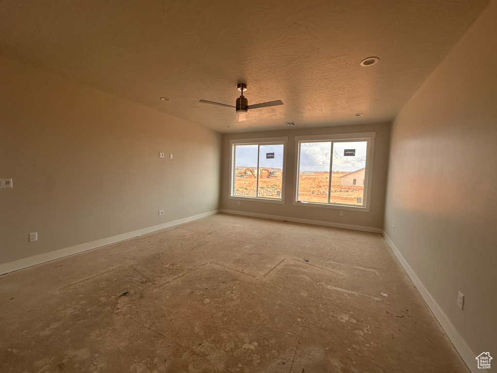 Empty room featuring a ceiling fan and a textured ceiling
