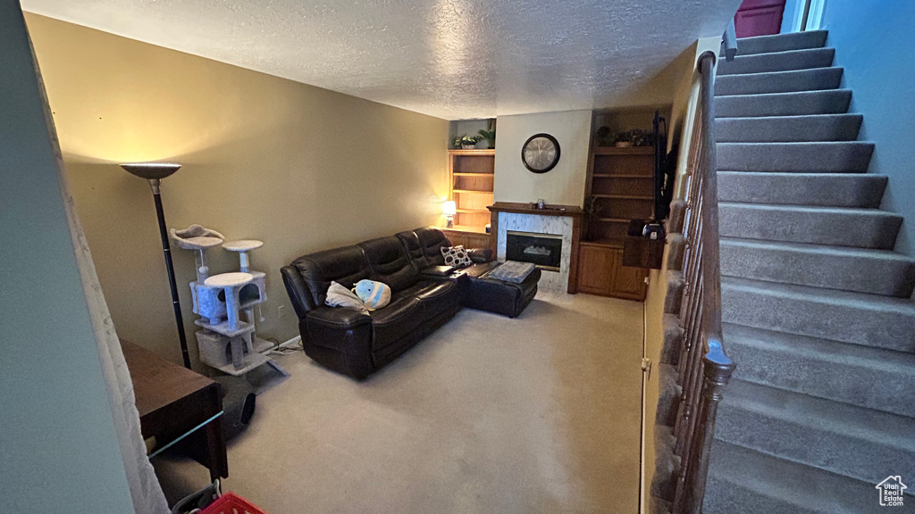 Living room featuring carpet flooring, stairs, and a textured ceiling