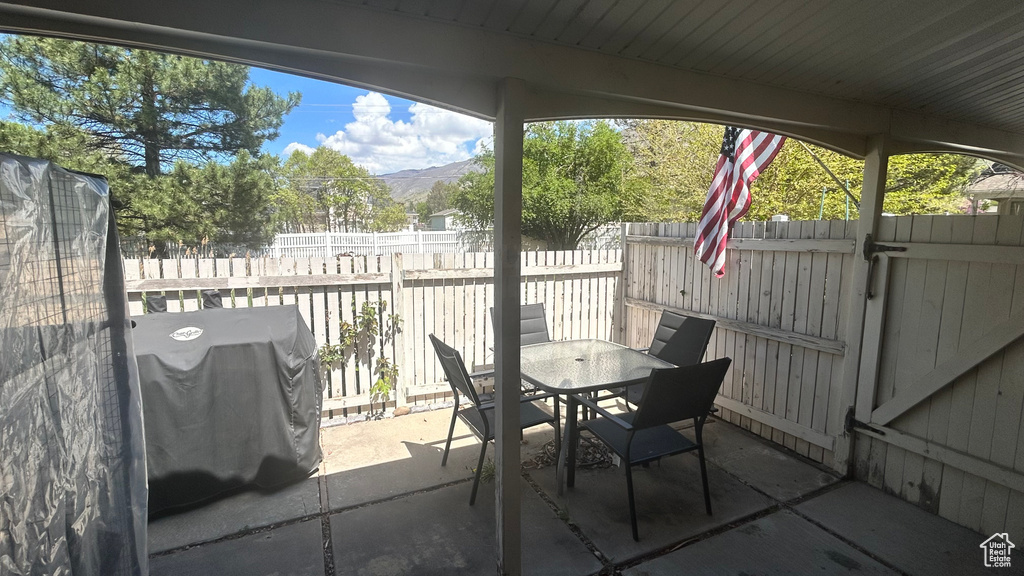 View of patio / terrace featuring outdoor dining area, a fenced backyard, a mountain view, and grilling area