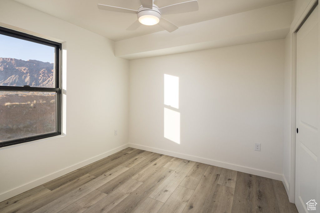Empty room with baseboards, wood finished floors, and a ceiling fan