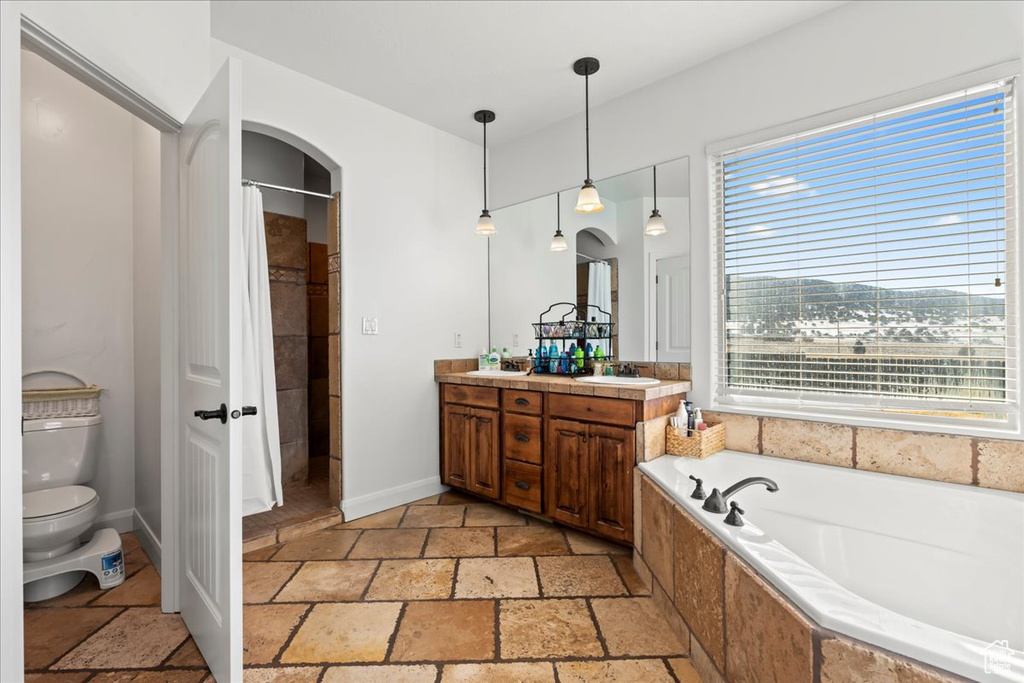 Full bathroom with shower with separate bathtub, vanity, and toilet