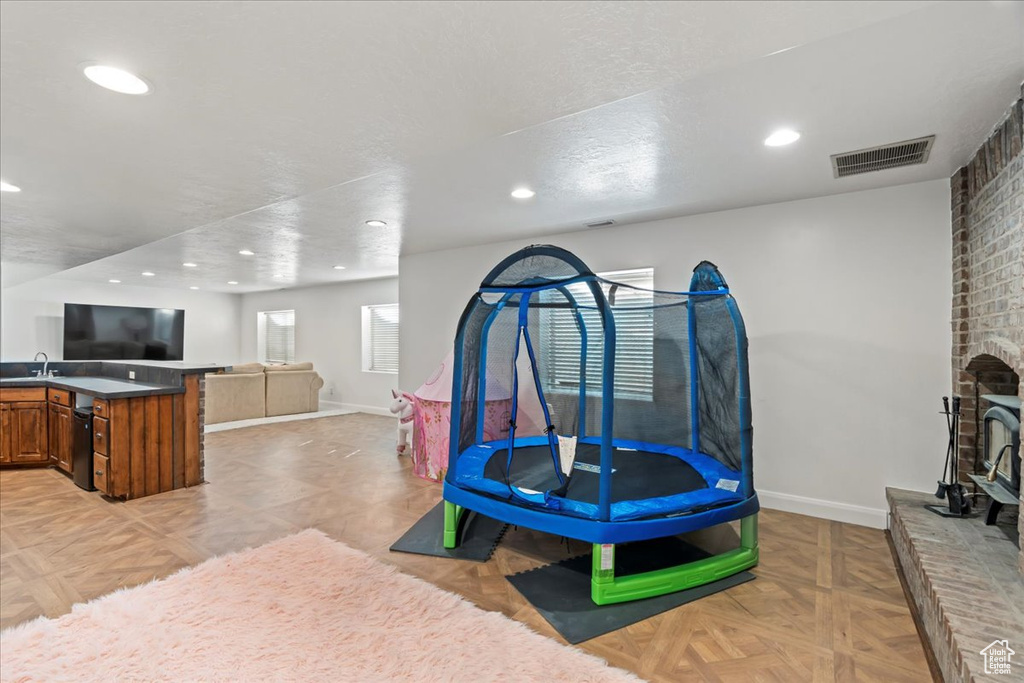 Game room featuring a fireplace, sink, and light parquet floors