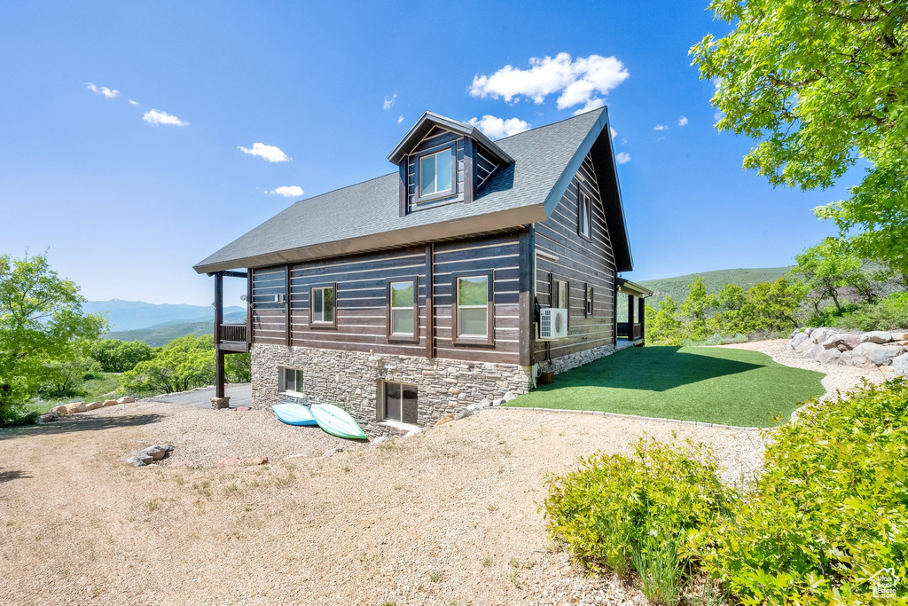 View of side of home with a lawn, a mountain view, and a shingled roof