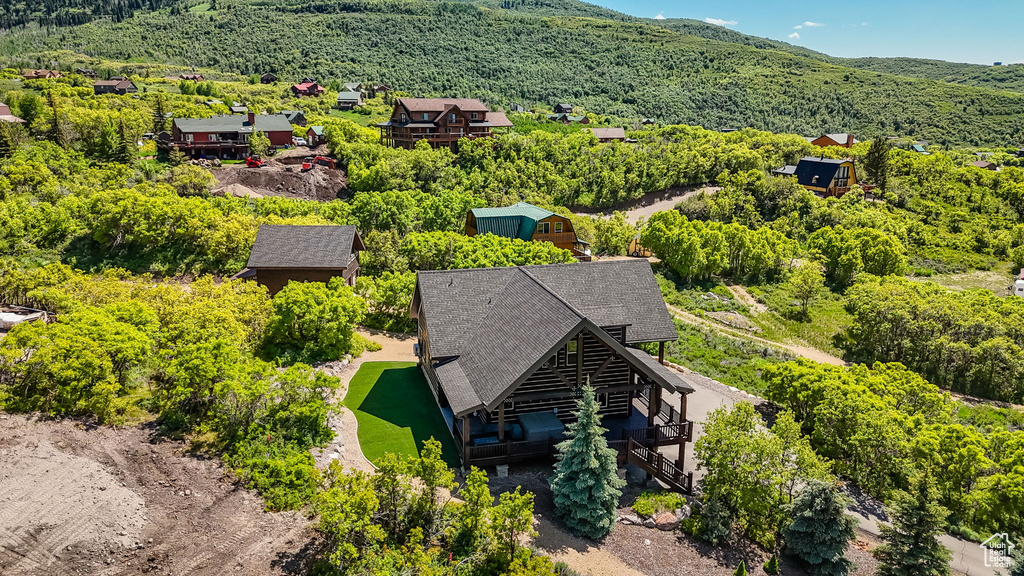 Aerial view of property and surrounding area with a mountainous background and a heavily wooded area