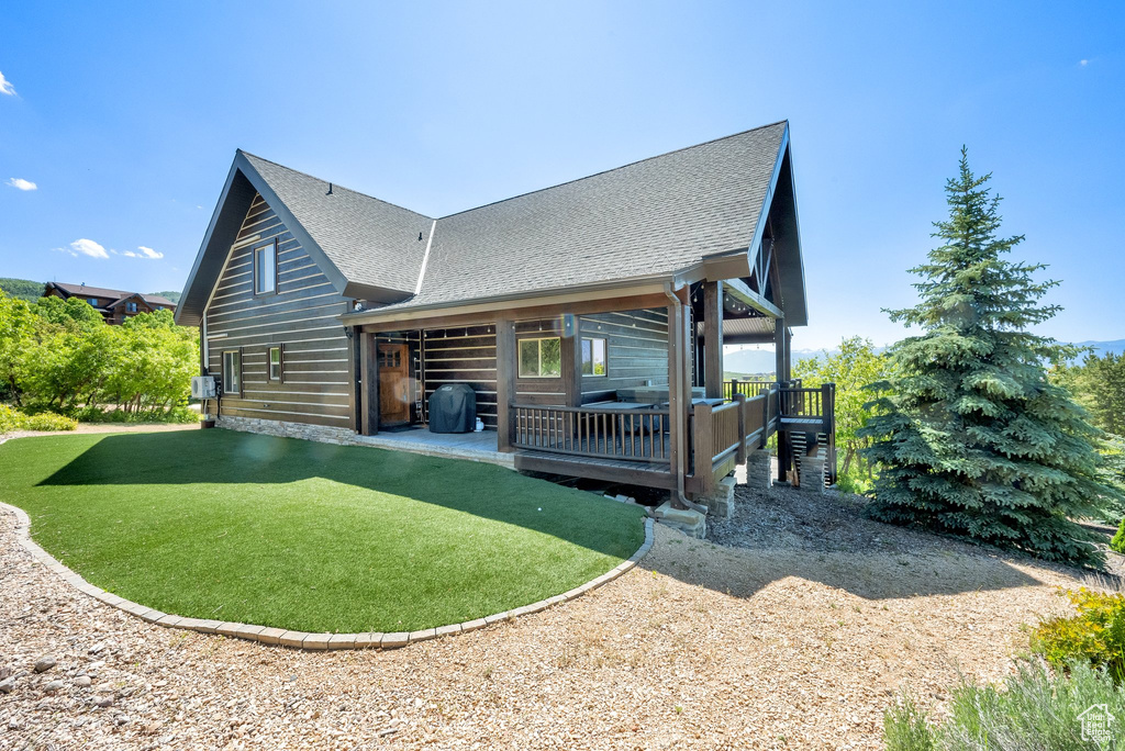 Back of property with roof with shingles and a patio area