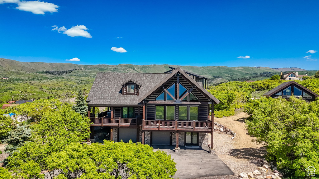 Log home featuring an attached garage, asphalt driveway, stone siding, and a mountain view