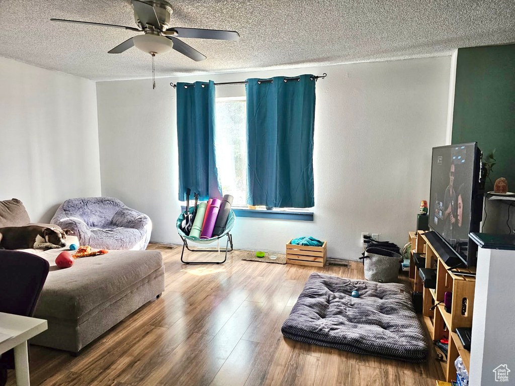 Living area featuring a textured ceiling, a ceiling fan, and wood finished floors