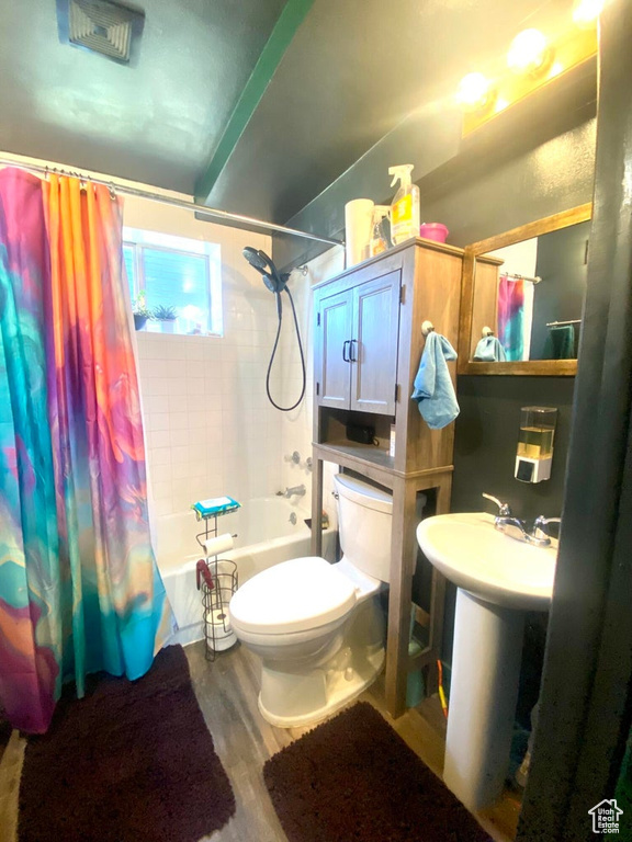Full bathroom with shower / tub combo, sink, hardwood / wood-style flooring, and toilet