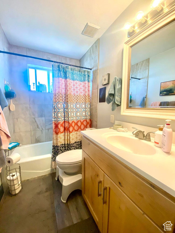 Full bathroom with shower / bathtub combination with curtain, vanity, and toilet