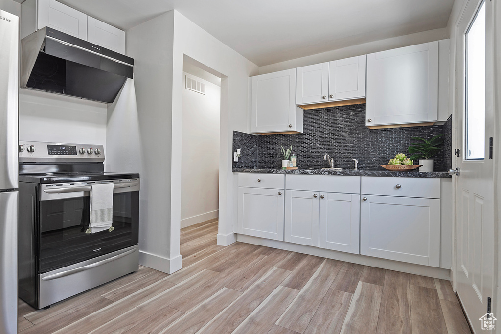 Kitchen featuring white cabinetry, stainless steel electric range oven, ventilation hood, and light wood-type flooring