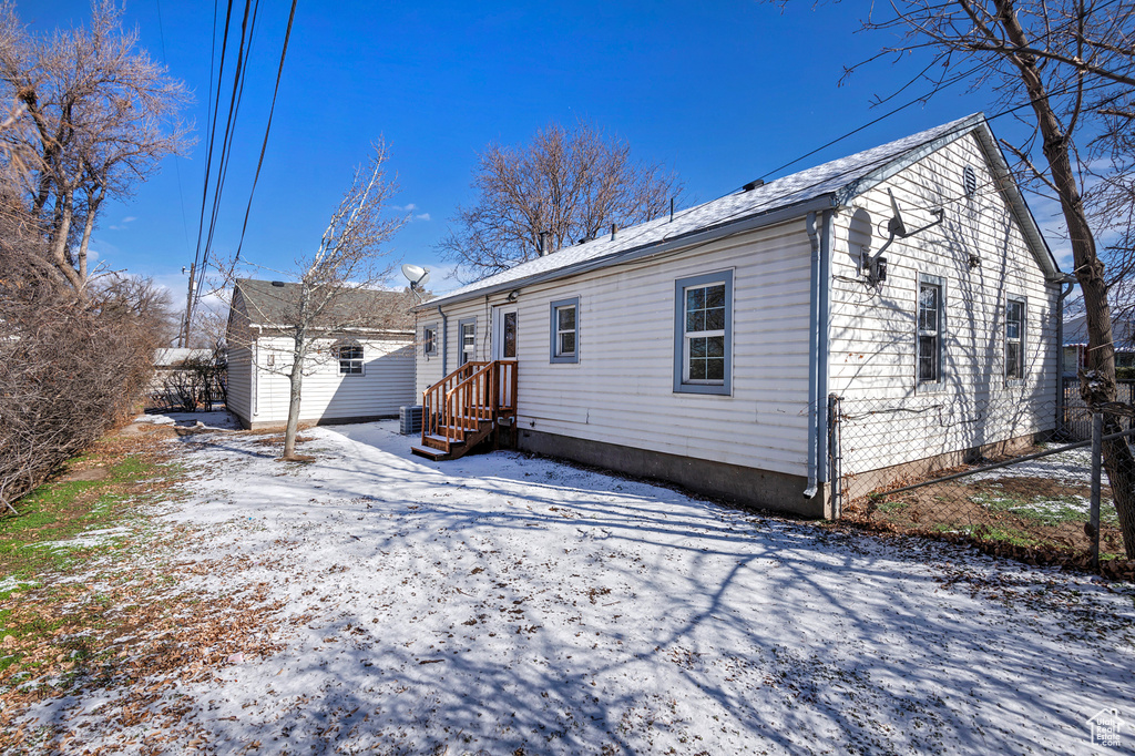 Snow covered back of property featuring a shed