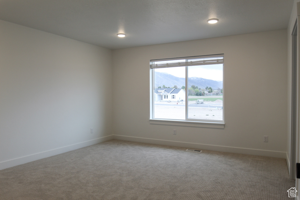 Unfurnished room with baseboards, light colored carpet, and a mountain view