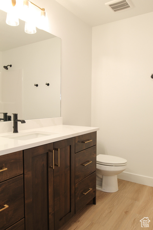 Full bath with wood finished floors, vanity, toilet, and baseboards