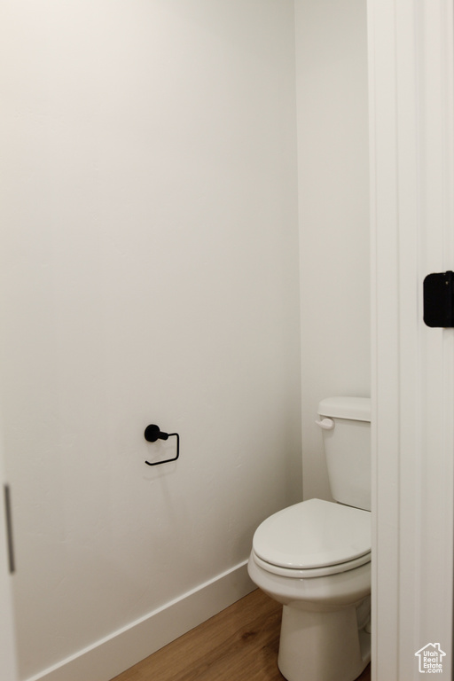 Bathroom with wood finished floors, baseboards, and toilet