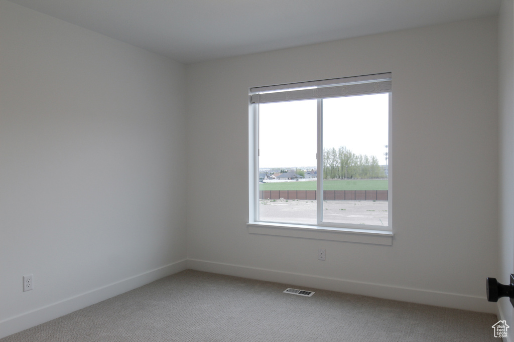 Spare room featuring light carpet and baseboards