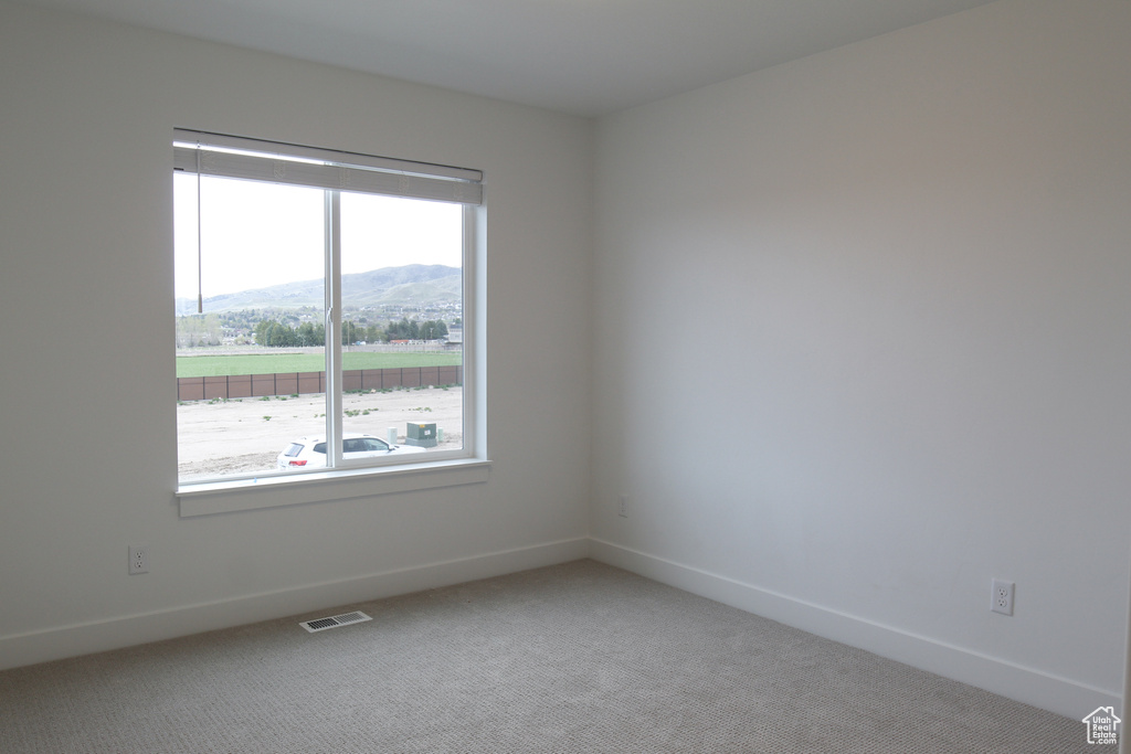 Spare room with a mountain view, light carpet, and baseboards