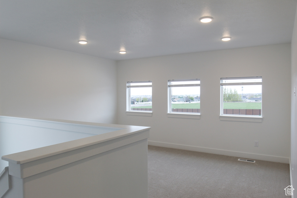 Empty room featuring light carpet, baseboards, and recessed lighting