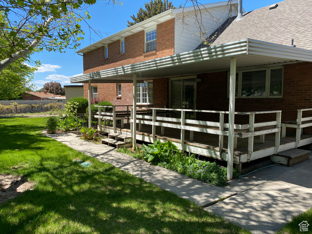 Back of house featuring brick siding, a yard, and a deck