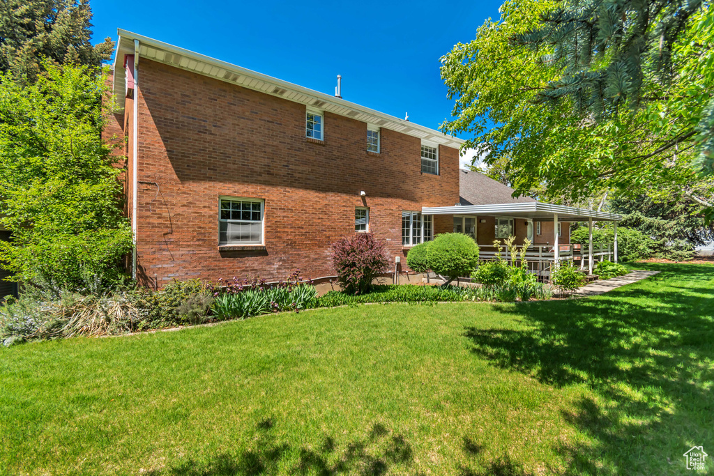 Rear view of property with a lawn and brick siding