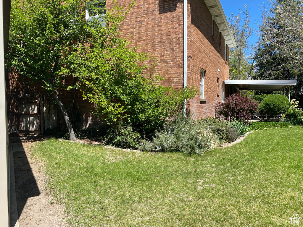 View of side of property with a lawn and brick siding
