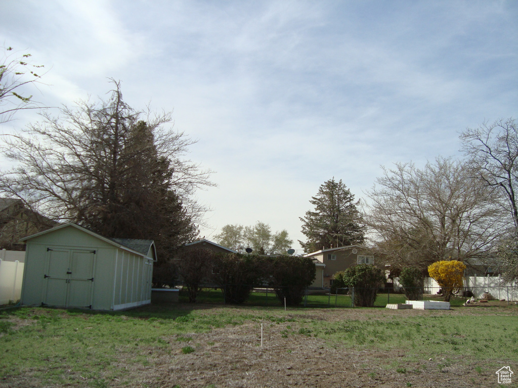 View of yard with an outdoor structure, fence, and a shed