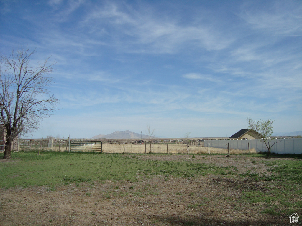 View of yard with a mountain view, fence, and a rural view