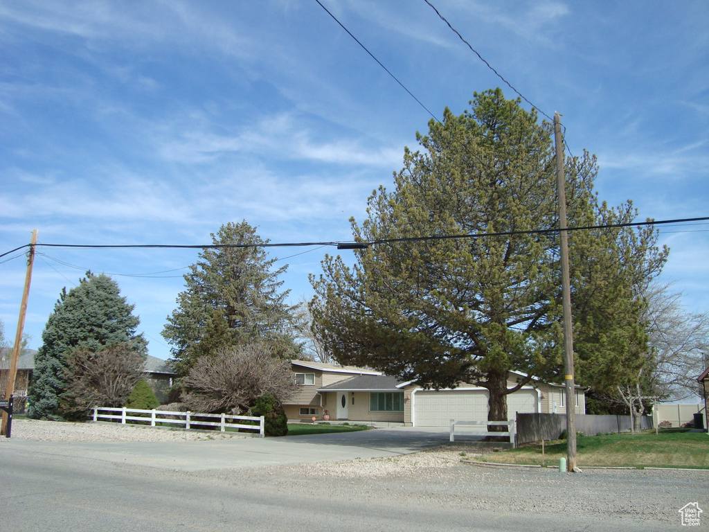 View of front of home with a garage, fence, and driveway