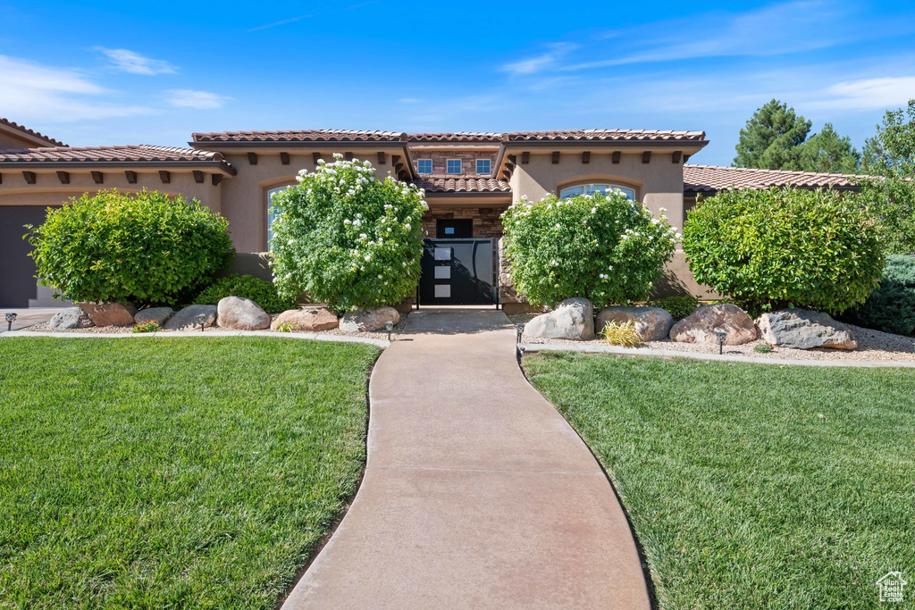 Mediterranean / spanish-style home with stucco siding, a tiled roof, and a front lawn