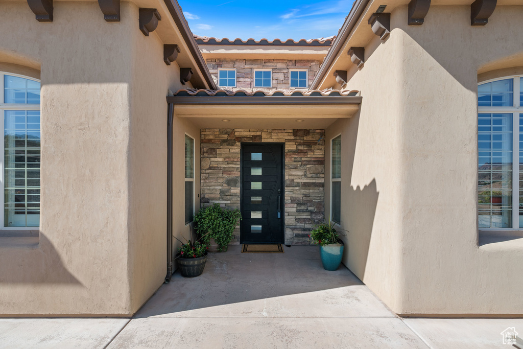 Property entrance featuring stone siding, a tile roof, and stucco siding